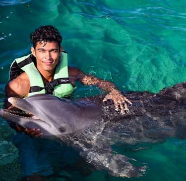 a man in a life jacket is holding a dolphin dolphines punta cana