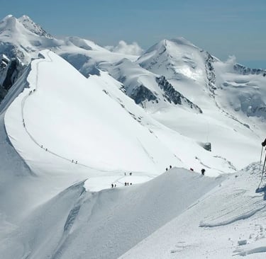 Group of hikers climbing the snowy ridge of Mount Breithorn towards the summit in the Swiss Alps