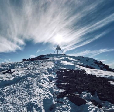 Summit of Mount Toubkal in Morocco with a metal marker and clouds in the background