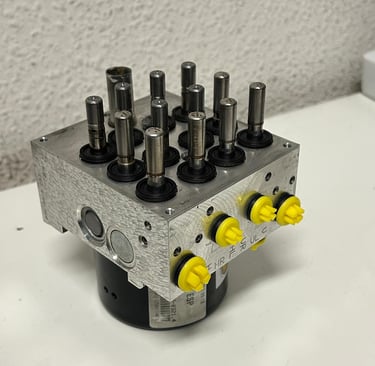 FOTO DESDE ARRIBA DE BOMBA HIDRAULICA DE ABS DESTAPADO Y RECIEN REPARADO CON TAPONES AMARILLOS DE CLAIRICAR EN LOS CANALES