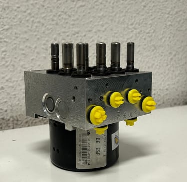 FOTO DEL COSTADO BOMBA HIDRAULICA DE ABS DESTAPADO Y RECIEN REPARADO CON TAPONES AMARILLOS DE CLAIRICAR EN LOS CANALES