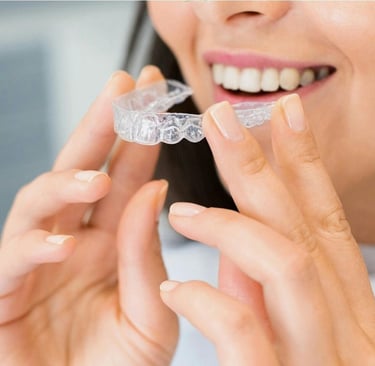 A girl holding clear castle transparent aligners in hand to wear for her tooth alignment