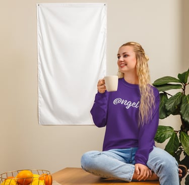 a woman in purple @ngel sweatshirt sitting on a table with a cup of coffee