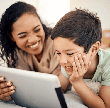 Mãe e filho estudam juntos com aplicativo educacional, reforçando psicopedagogia familiar