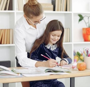 Criança sorrindo enquanto faz tarefa com ajuda da Psicopedagoga, representando apoio à aprendizagem