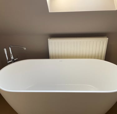 Ligbad met chromen kraan en een radiator in compacte badkamer