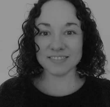 a woman with dark, curly hair and a black sweater. She is smiling.