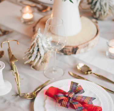 a table setting with a red napkin and a vase with flowers