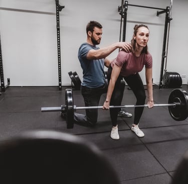Ein Trainer korrigiert die Bewegungsausführung beim Hanteltraining