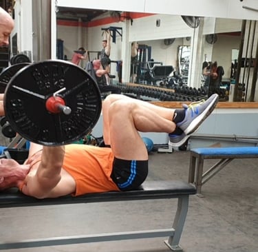 A top Gym coach carefully spotting a man doing a bench press in a gym