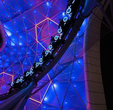 a roller coaster with a blue lit canopy background