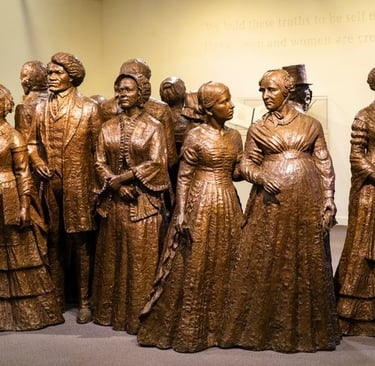 a group of bronze statues of women in dresses