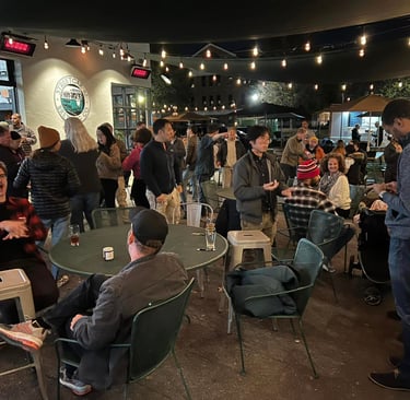 a group of people sitting at or standing around tables in a brewery
