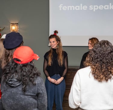 Women looking at female public speaking trainer, beamer in back showing: female speaking berlin