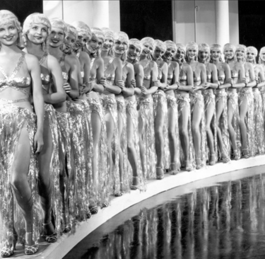 Line of Whoopee! (1930) chorus girls in gold lamé and blonde wigs standing beside a reflecting pool.