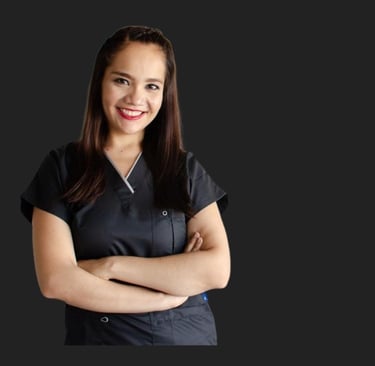 Smiling female medical professional in dark grey scrubs with arms crossed against a black background.