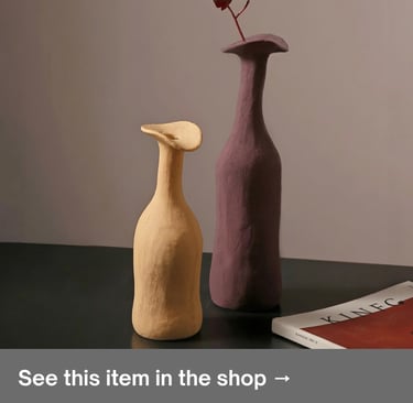 Textured beige and mauve minimalist clay vases next to a magazine for Scandinavian home decor.