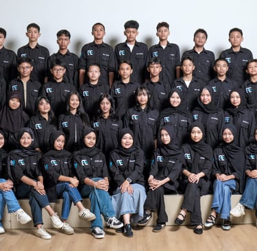 Group of Indonesian students in matching black uniform shirts posing for a professional school class portrait.