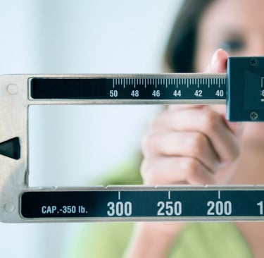 A woman adjusts the sliding weights on a professional physician beam scale to measure body weight.