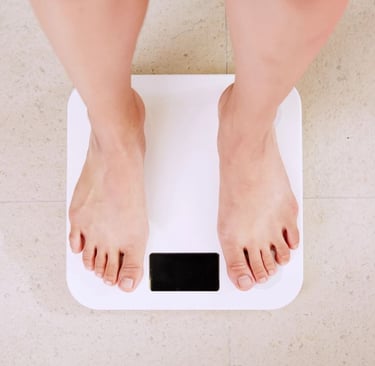 A person standing on a white digital bathroom scale for weight measurement and fitness tracking.