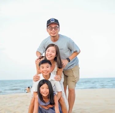 young asian family on a beach smiling with 2 young children