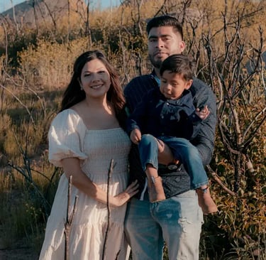 young latin family smiling in a field plain at sunset with a young toddler