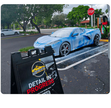A blue Chevrolet Corvette C8 covered in white foam during a professional mobile car detailing service.