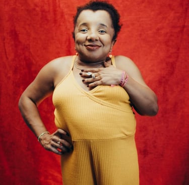 Foto de Roberta Holiday. Mulher negra com nanismo, de cabelos crespos curtos, macacão amarelo.