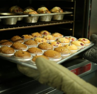 Muffins de arándano recién horneados siendo retirados de un horno 