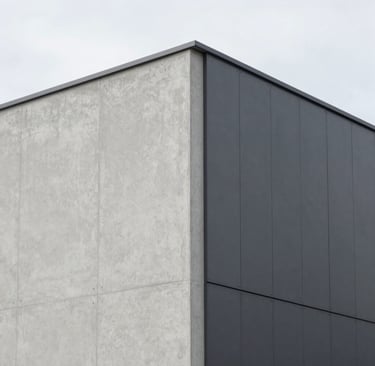An architectural detail shot of a modern, minimalist building facade in Northern Europe. The image focuses on the sharp, clean intersection of light gray concrete and dark gray metal panels. Sophisticated simplicity and precision are highlighted by the soft, overcast daylight. Artistic and professional composition.