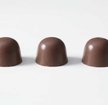 Three gourmet milk chocolate pralines arranged in a row on a white background.