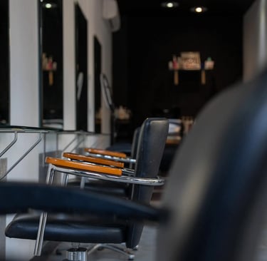 Modern hair salon interior featuring black styling chairs and minimalist mirrors.