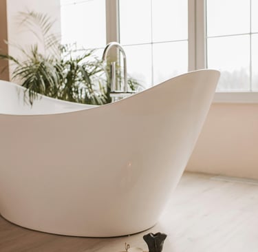 Luxury white bathtub with green fern and large window in background