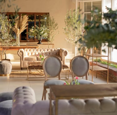 Luxury white chesterfield lounge in a well lit room surrounded by plants and other white furniture