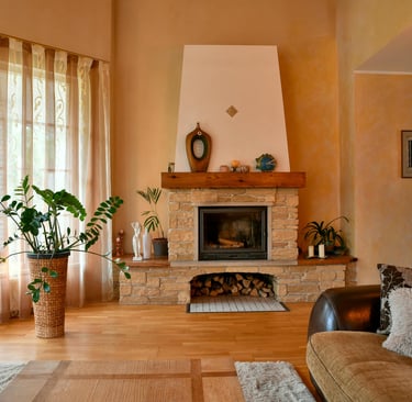 Light stone fireplace with wood storage inside luxury home. Large window and plant to the left