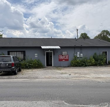 Tool Service Company building with a dark SUV parked in front under a cloudy sky.