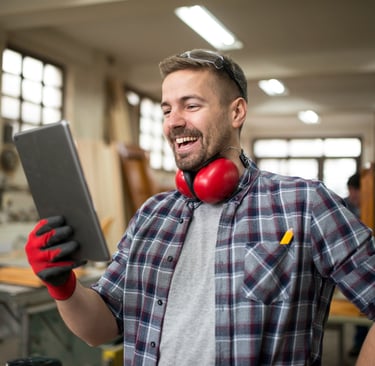 A smiling tradie in a workshop happy with his organised work schedule..