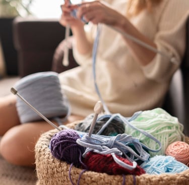 mujer sentada tejiendo un proyecto con trapillo azul cielo