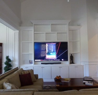 Custom white built-in media wall with bookcases and cabinetry in a Monmouth County home