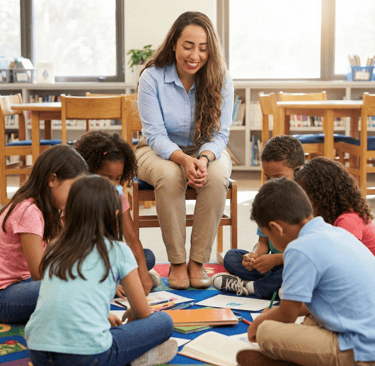 Julie Granata, especialista em TEA, sentada ao centro de um grupo de crianças realizando atividades educativas