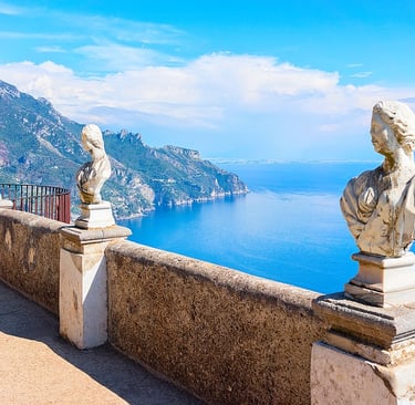 Classical marble busts on the Terrace of Infinity overlooking the blue Amalfi Coast in Ravello, Italy.