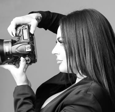 Professional female photographer holding a DSLR camera with a large lens in a studio setting.