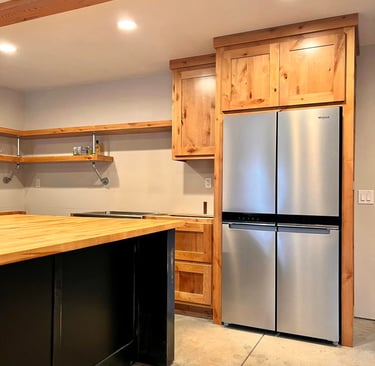 Rustic kitchen with wood cabinets, butcher block island, and stainless steel French door refrigerator.