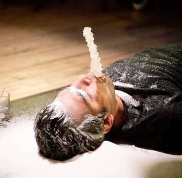 a man is lying on a floor with Sugar candy in the mouth of the artist,