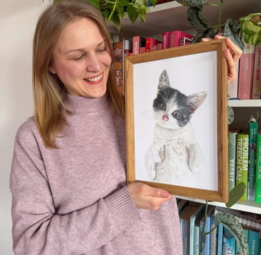 Pet portrait artist holding a framed realistic hand drawn custom cat drawing