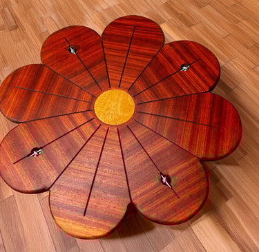 Handcrafted wooden tensegrity table shaped like a flower with mahogany petals on a hardwood floor.
