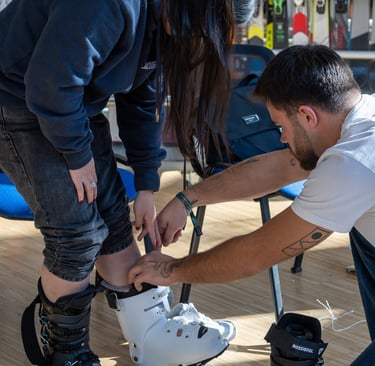 Professional ski shop technician fitting a customer with white Rossignol ski boots for a proper rental fit.
