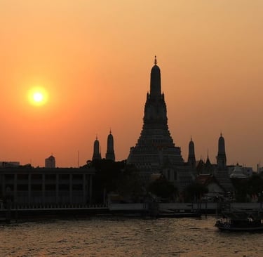 Silhouette des Wat Arun vor einem leuchtend orangefarbenen Sonnenuntergang über dem Chao-Phraya-Flus