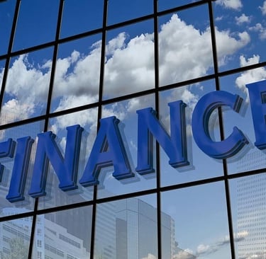 3D-Finanz-Schild an einem Glas-Bürogebäude mit Spiegelungen von weißen Wolken und blauem Himmel.