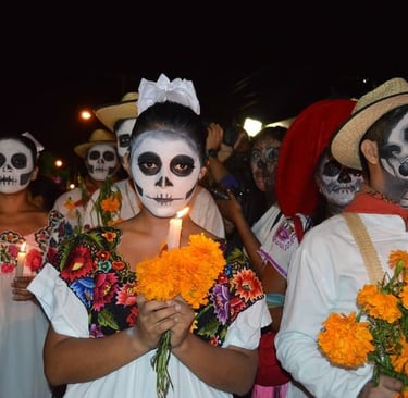 Menschen mit Totenkopf-Schminke feiern den Día de los Muertos bei Nacht mit Ringelblumen und Kerzen.